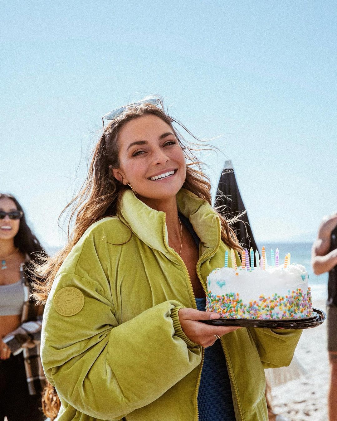 Women smiling on a Los Angeles Beach with a Birthday Cake under a Beach Cabana Rental Celebrating her Birthday